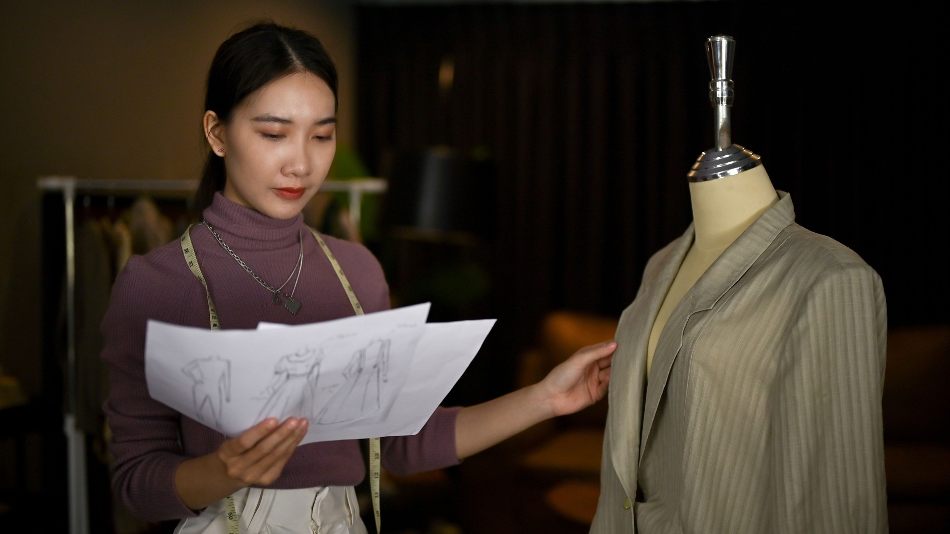 A fashion designer checking her new sample on a mannequin and working in her studio.